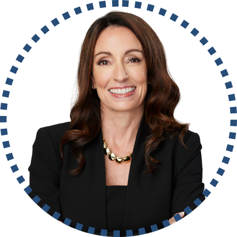 Smiling woman in a black blazer with wavy brown hair, wearing a gold necklace, framed by blue and white patterned circle; focus on rural health.